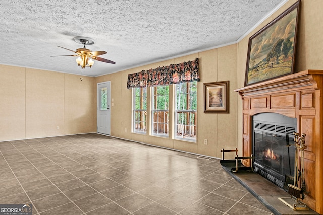 living room with ceiling fan, dark tile flooring, a tile fireplace, and a textured ceiling