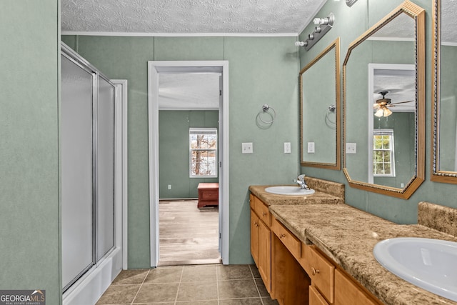 bathroom with tile floors, dual bowl vanity, a healthy amount of sunlight, and a textured ceiling