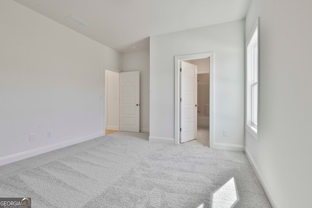 unfurnished bedroom featuring ensuite bathroom and light colored carpet