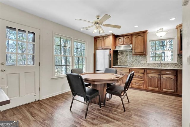 dining space with ceiling fan, light hardwood / wood-style floors, sink, and a healthy amount of sunlight