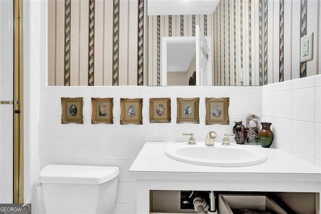 bathroom featuring tile walls, vanity, and toilet