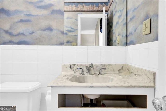 bathroom featuring vanity, tile walls, and toilet