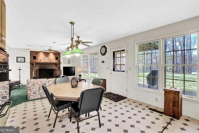 dining space featuring a brick fireplace and ceiling fan