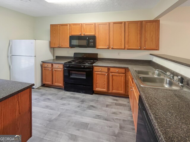 kitchen featuring sink, black appliances, a textured ceiling, and light hardwood / wood-style flooring