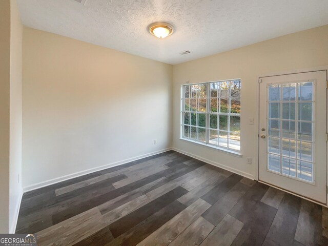 empty room featuring dark hardwood / wood-style flooring and a textured ceiling