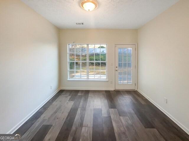 spare room featuring dark hardwood / wood-style flooring and a textured ceiling