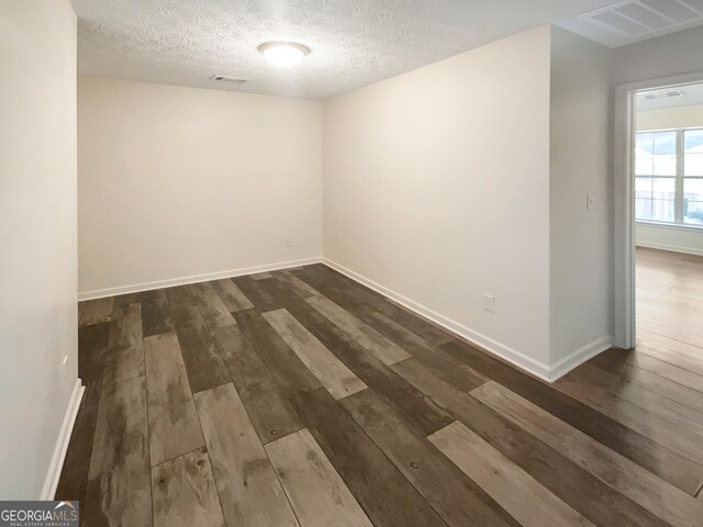 spare room featuring dark hardwood / wood-style floors and a textured ceiling