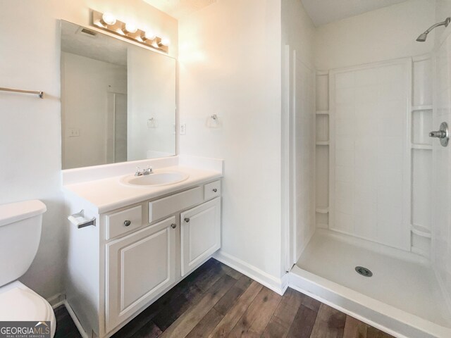 bathroom with wood-type flooring, vanity, toilet, and walk in shower