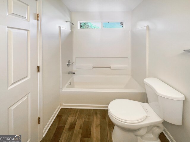 bathroom featuring bathtub / shower combination, hardwood / wood-style flooring, and toilet