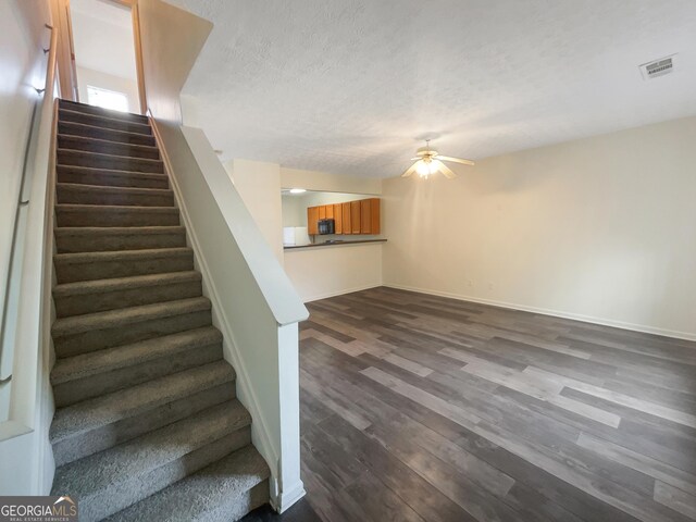 stairway with hardwood / wood-style flooring, ceiling fan, and a textured ceiling