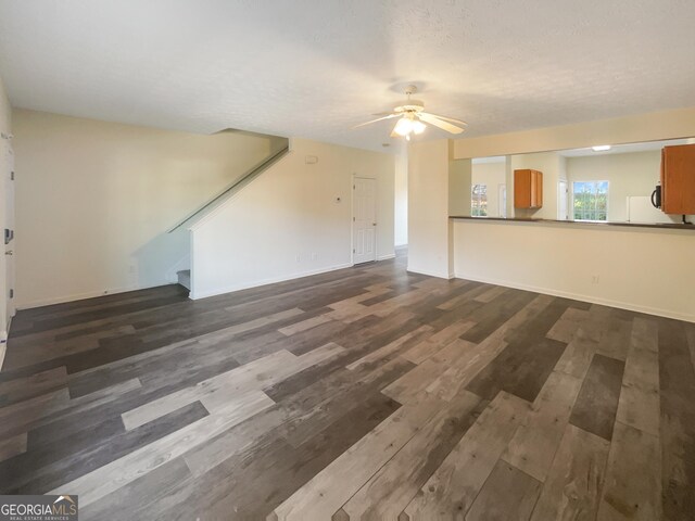 unfurnished living room with a textured ceiling, dark hardwood / wood-style floors, and ceiling fan