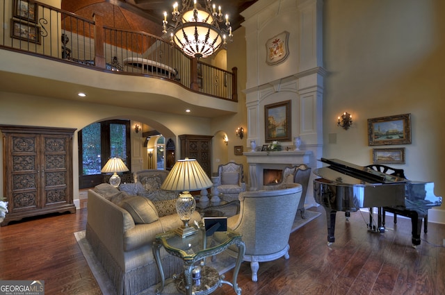 living room featuring dark wood-type flooring, a chandelier, and a high ceiling