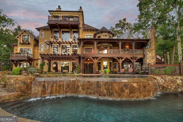 back house at dusk with a balcony