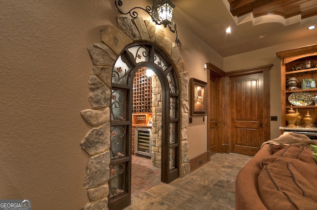 wine room with beamed ceiling and wine cooler