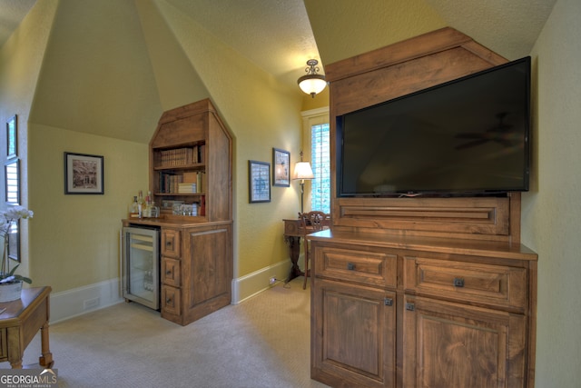 interior space with a textured ceiling, beverage cooler, and lofted ceiling