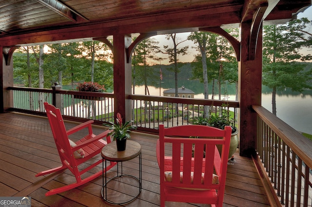 deck at dusk featuring a water view