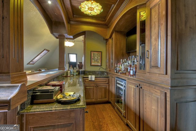 bar featuring beverage cooler, hardwood / wood-style flooring, dark stone counters, and ornamental molding