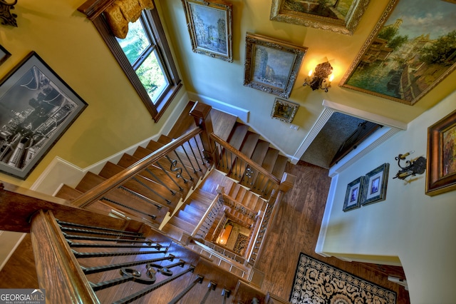 stairway featuring a fireplace, a towering ceiling, and wood-type flooring