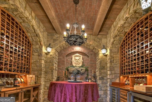 wine area featuring an inviting chandelier, wine cooler, and beam ceiling