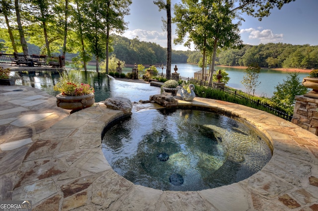 view of swimming pool featuring a water view and an in ground hot tub