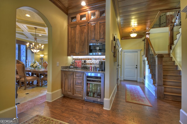 kitchen featuring dark wood-type flooring, beverage cooler, stone counters, and a notable chandelier