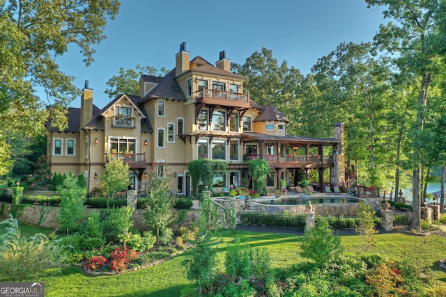 rear view of property with a balcony and a yard