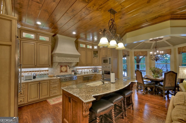 kitchen featuring a kitchen island with sink, custom exhaust hood, a chandelier, hanging light fixtures, and appliances with stainless steel finishes