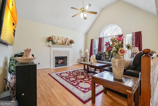 living room with a fireplace, ceiling fan, hardwood / wood-style floors, and high vaulted ceiling