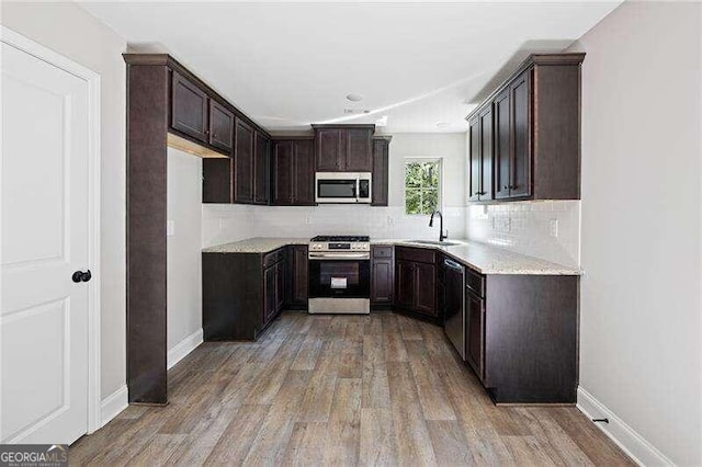 kitchen with dark brown cabinetry, sink, light wood-type flooring, appliances with stainless steel finishes, and decorative backsplash