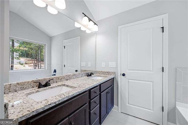 bathroom with tile patterned flooring, vanity, and lofted ceiling