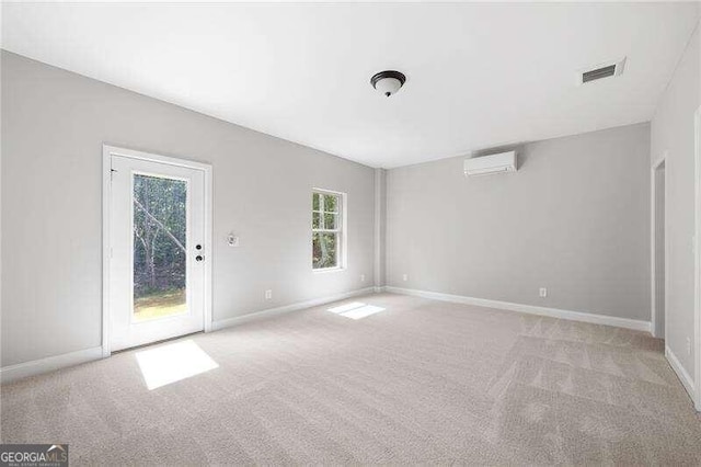 spare room featuring an AC wall unit and light carpet