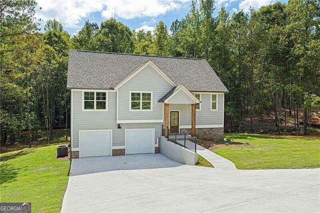 bi-level home featuring a garage, a front lawn, and central air condition unit