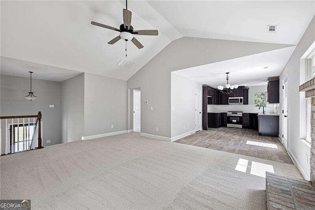 unfurnished living room featuring light colored carpet, high vaulted ceiling, sink, and ceiling fan with notable chandelier