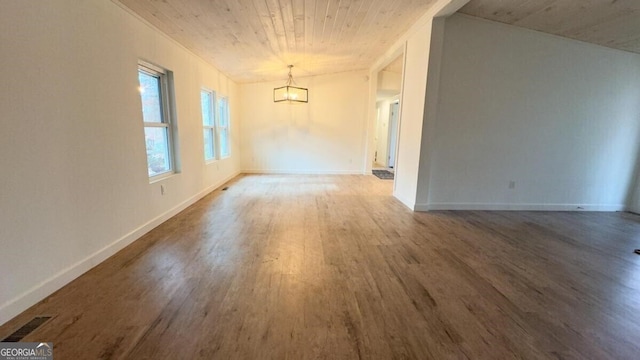 spare room with an inviting chandelier and dark hardwood / wood-style flooring