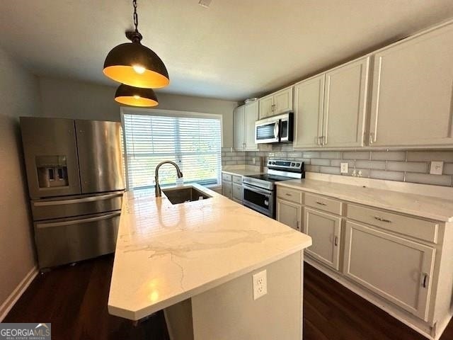 kitchen featuring an island with sink, appliances with stainless steel finishes, sink, and light stone counters