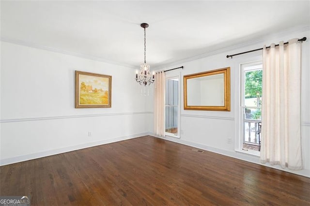 unfurnished room featuring dark hardwood / wood-style floors, an inviting chandelier, and ornamental molding