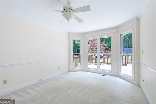 spare room featuring light colored carpet, ceiling fan, and crown molding