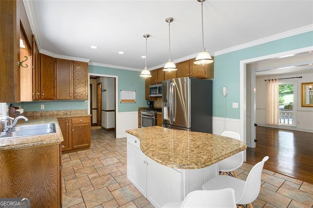 kitchen with sink, a center island, stainless steel appliances, decorative light fixtures, and ornamental molding