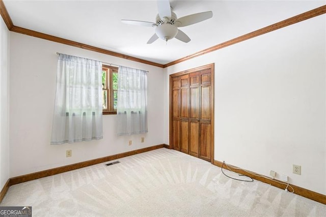 unfurnished bedroom with ceiling fan, a closet, carpet floors, and ornamental molding