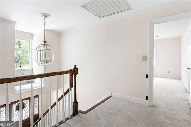 hallway featuring a notable chandelier, ornamental molding, and light carpet