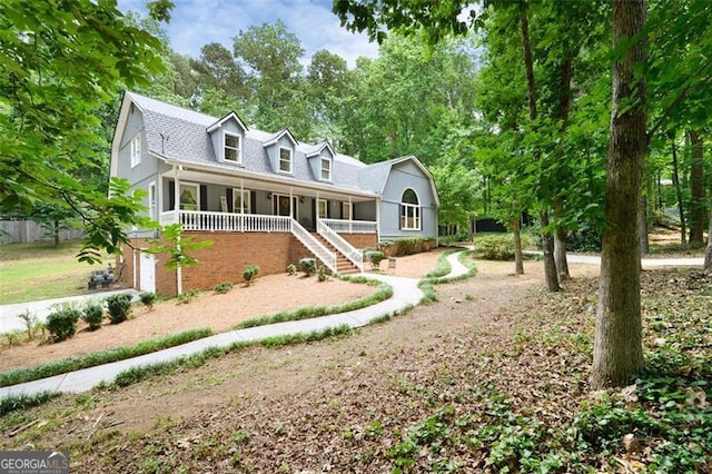 cape cod home featuring a porch and a garage