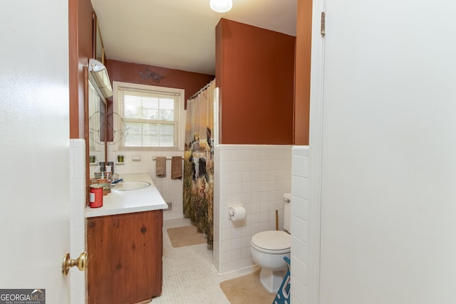 bathroom featuring tile patterned floors, vanity, toilet, and tile walls