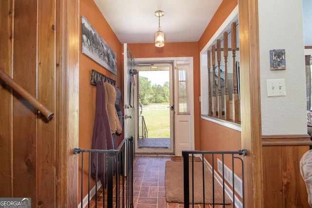 doorway to outside with wood walls