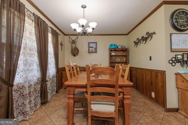 dining space with a chandelier, light tile patterned floors, wooden walls, and ornamental molding