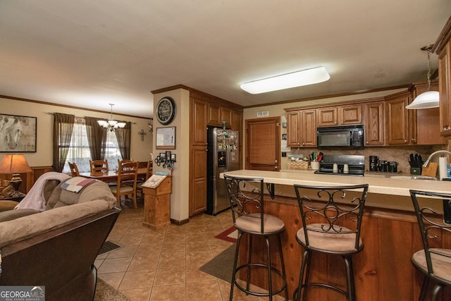 kitchen featuring ornamental molding, pendant lighting, stainless steel refrigerator with ice dispenser, and an inviting chandelier