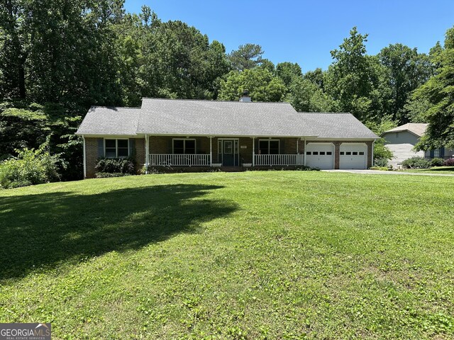 ranch-style home featuring covered porch, a front yard, and a garage