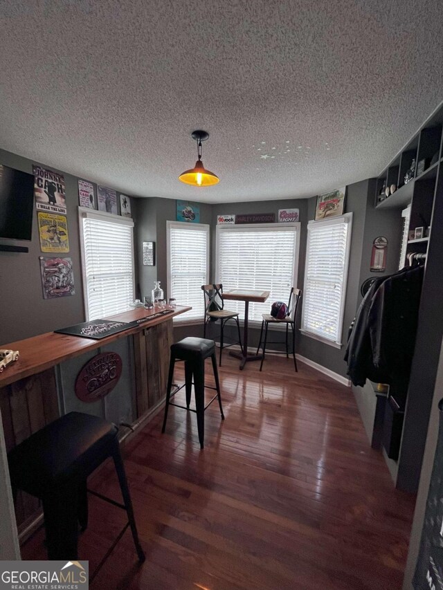 dining space with dark wood-type flooring and a textured ceiling