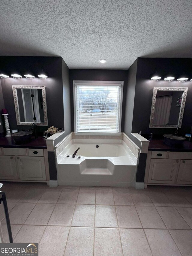 bathroom featuring tile patterned flooring, a textured ceiling, vanity, and a bathtub