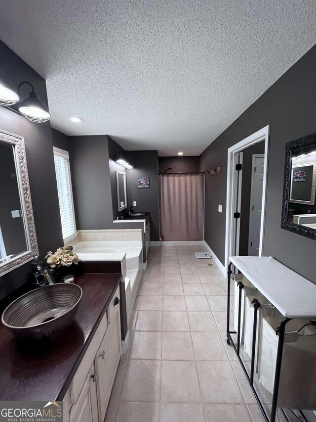 bathroom featuring tile patterned flooring, a bath, vanity, and a textured ceiling