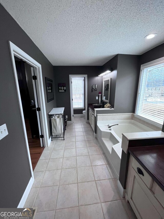 bathroom with a tub, tile patterned floors, and a textured ceiling